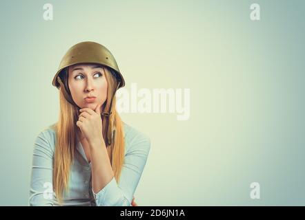 Thoughtful Woman in military armor cap equipment of of World War II period looking to side copyspace pensive. Caucasian person in white formal shirt, Stock Photo