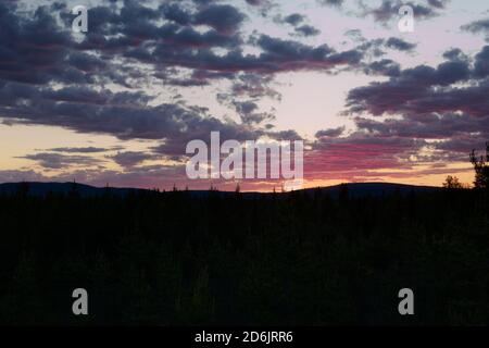 Dusk and pink colored clouds over the mountains Bredtraskliden and Svartliden in southern Lapland. Stock Photo