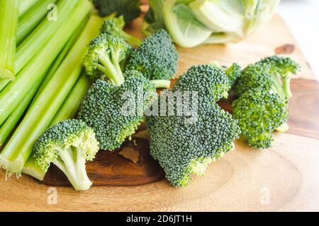 Celery, broccoli, cauliflower close up on wooden cutting board. Fresh raw organic vegetables close up on kitchen table Stock Photo