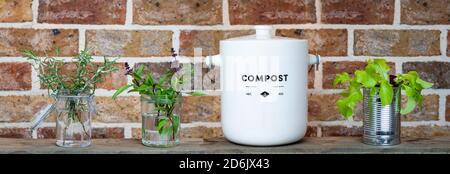 Kitchen waste compost pot and reused jars and tin on kitchen shelf. Recycle and reuse for zero waste and grow your own food Stock Photo