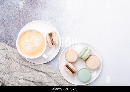 Cup of coffee, sweater and macarons on stone background. Copy space. Flat lay, top view - Image Stock Photo