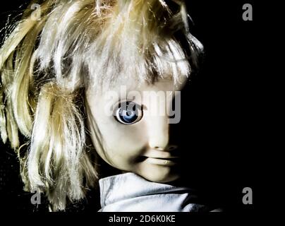 Creepy girl doll face. It seems like character of horror movie. Angry baby doll, fear of living ghost. Halloween concept. Low-key lighting. Isolated o Stock Photo