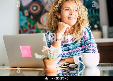 Portrait of beautiful blonde caucasian woman smile and work with laptop computer at home - concept of alternative office and freedom with smart work t Stock Photo