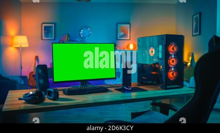Powerful Personal Computer Gamer Rig with Mock Up Green Screen Monitor Stands on the Table at Home. Cozy Room with Modern Design is Lit with Warm and Stock Photo