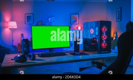 Powerful Personal Computer Gamer Rig with Mock Up Green Screen Monitor Stands on the Table at Home. Cozy Room with Modern Design is Lit with Pink Neon Stock Photo