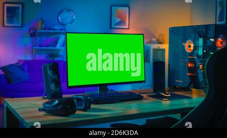 Powerful Personal Computer Gamer Rig with Mock Up Green Screen Monitor Stands on the Table at Home. Cozy Room with Modern Design is Lit with Warm and Stock Photo