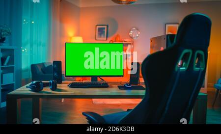 Powerful Personal Computer Gamer Rig with Mock Up Green Screen Monitor Stands on the Table at Home. Cozy Room with Modern Design is Lit with Warm and Stock Photo