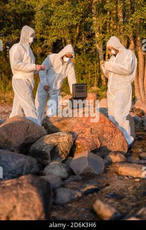Researchers in team with container at beach taking water samples Stock Photo