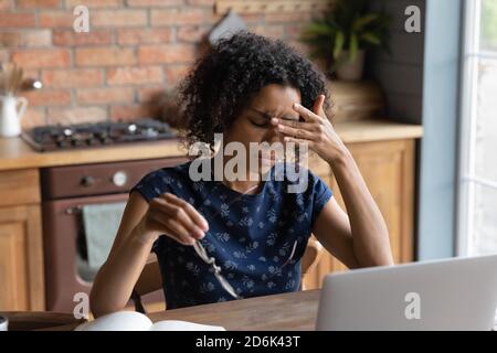 Tired biracial woman suffer from migraine working on laptop Stock Photo