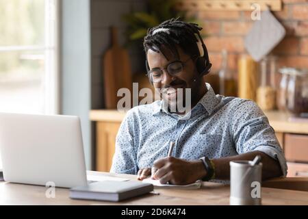 Smiling biracial man in headphones study online on computer Stock Photo