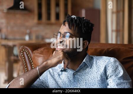 Happy biracial man relax on sofa dreaming or planning Stock Photo