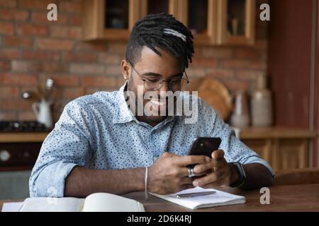 Smiling biracial man use modern cellphone texting Stock Photo