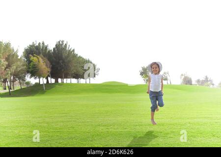 Cheerful cute child in moment of jumping above green meadow in summer on sunny day Stock Photo