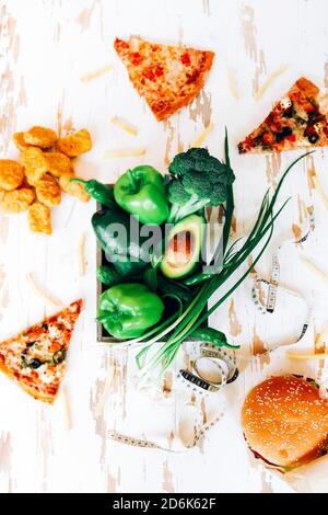 Top view of fresh green vegetables placed on table with various fast food Stock Photo