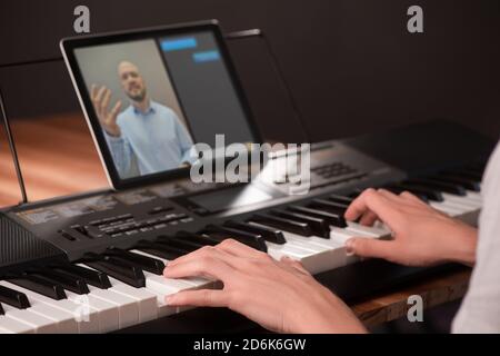 Young man learning to play piano, using keyboard and tablet with app Stock Photo