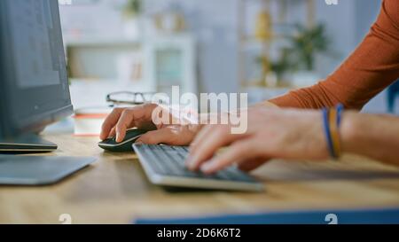 Handsome Software Engineer Works on a UX / UI Mobile App Template, Uses Personal Computer. Freelance Programmer Working from Cozy Living Room. Stock Photo