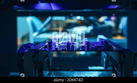 Automated Robotic Industrial Equipment is Testing Electronic Printed Circuit Board with Purpule Neon Light and Laser Technology After Assembly. Stock Photo
