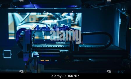 Automated Robotic Industrial Equipment is Testing Electronic Printed Circuit Board with Blue Neon Light and Laser Technology After Assembly. Stock Photo