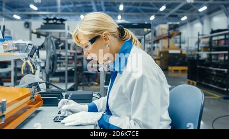 Senior Electronics Factory Worker in White Work Coats Inserting Microchips, Processors and Semiconductors into Printed Circuit Boards for Smartphones Stock Photo