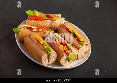 Delicious sandwiches with ham vegetables and sauce close up on a dark table, close up Stock Photo