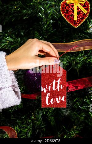 Decorating Christmas tree, hand putting Christmas decorations on fir branches. Christmas hanging decorations. Stock Photo