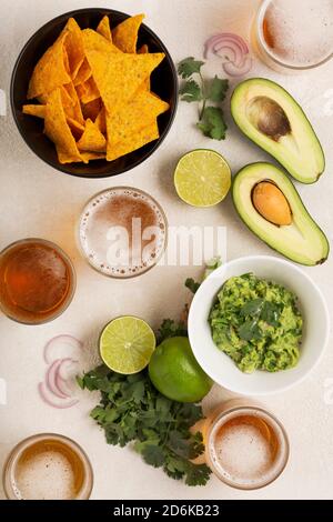 light Mexican snack or dinner Guacamole, corn chips and beer, top view Stock Photo