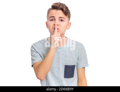 Handsome teen boy keeps fore finger on lips, asking for silence, isolated on white background Stock Photo