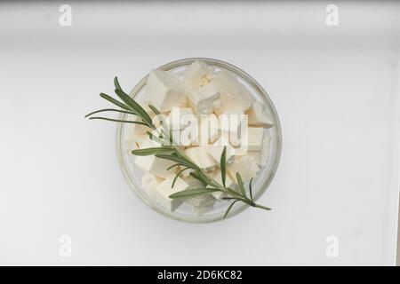 Feta cheese closeup cut into cubes in a transparent bowl, top view Stock Photo