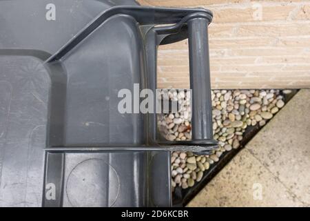 Abstract view of a typical household waste wheelie bin seen located outside a kitchen wall at a private property. Stock Photo
