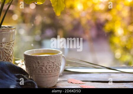Hot cup of tea on the background of an autumn day. White cup with tea and lemon on a wooden windowsill with autumn leaves. Cozy concept. Copy space Stock Photo