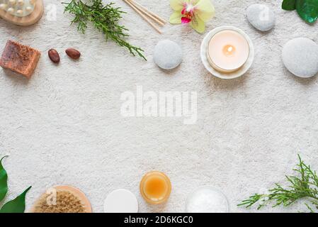 Natural Skin Care and Spa Set on white soft towel background with natural cosmetic products, flower, green leaves, candle and zen like stones. Relax c Stock Photo