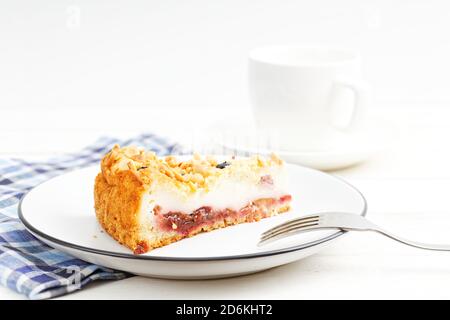 Piece of cake with cottage cheese souffle and plum decorated with almonds and blueberries on white wooden table Stock Photo
