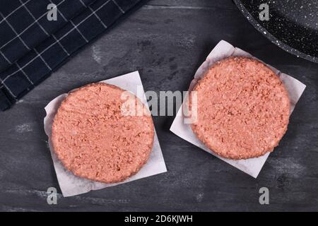 Two raw round vegan soy based burger patties on dark background Stock Photo