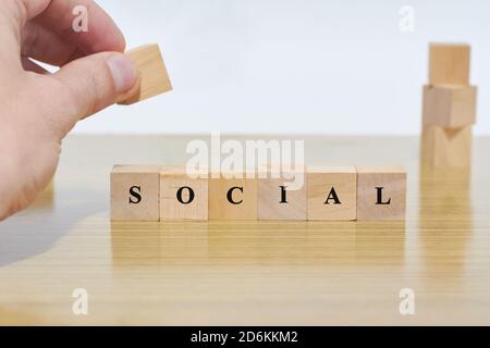 SOCIAL word written on wooden cubes blocks on light background. Hand holding wood block. Social concept Stock Photo
