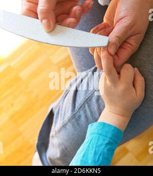 Hands of a woman filing the toenails of a child Stock Photo