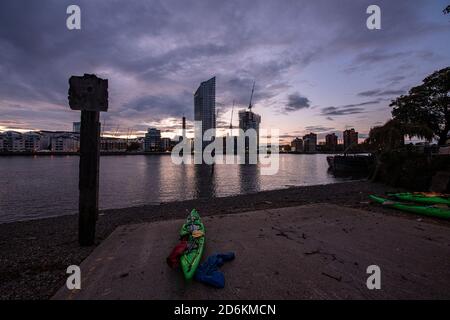 Canoes on the banks of the River Thames in Battersea with the Chelsea waterfront opposite Stock Photo