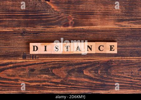 DISTANCE word written in cube on wooden floor. Concept of social distancing Stock Photo