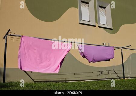 Pink and violet bed sheets hanging on a drying rack in the garden (Pesaro, Italy, Europe) Stock Photo