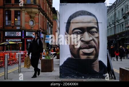 Manchester / United Kingdom - October 17, 2020: Manchesters George Floyd mural and young man in medical mask passing by it. Stock Photo