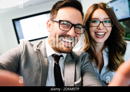 Young happy colleagues having fun while taking selfie in office. Stock Photo