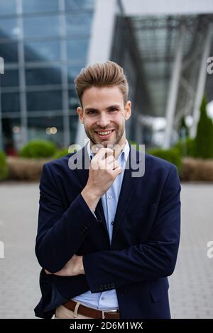 Portrait of handsome smiling man in casual wear. Successful young businessman.Young man standing on the city street near business center Stock Photo