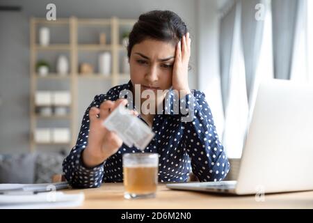 Indian woman touch head pouring into glass anti hangover remedy Stock Photo