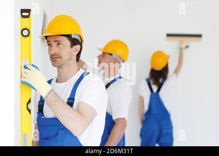 Group of smiling builders in hardhats with tools indoors building, teamwork and people concept Stock Photo
