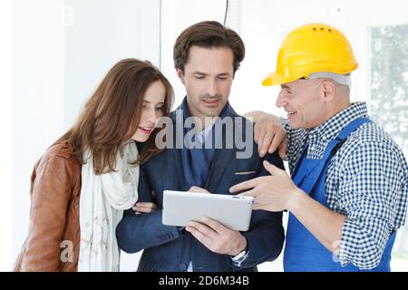 Worker and couple using tablet pc at construction site planning renovation house design plans Stock Photo