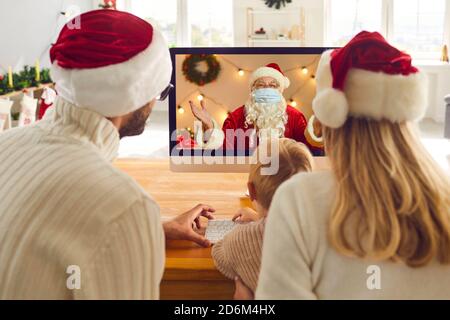 Parents and their little child having live video chat with Santa Claus during lockdown period Stock Photo