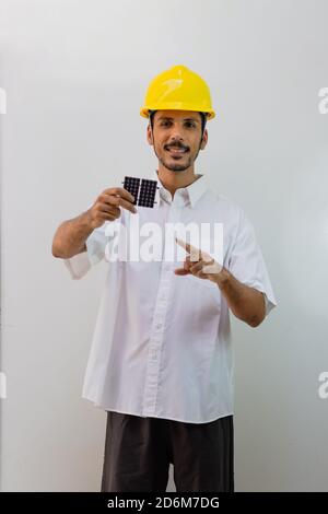 Worker with helmet holding a photovoltaic solar panel isolated on white background. Stock Photo