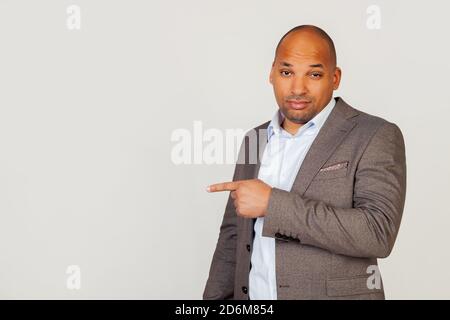 Young male African American businessman with a flirtatious expression, pointing his finger and frowning, squinting in confusion, seriously thinking about a difficult problem. Stock Photo