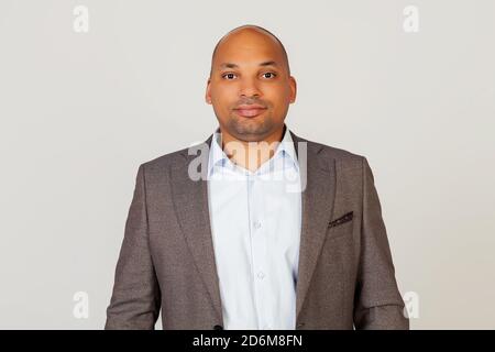 Portrait of a young African American guy businessman smiling and looking at the camera, looking trustworthy and sincere with a friendly kind smile, standing against gray background Stock Photo