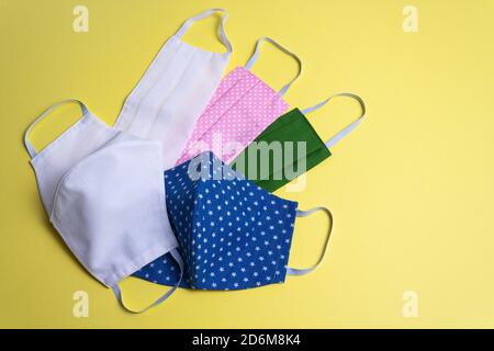 Five colored different reusable medical masks on yellow isolated background. Hygienic, antimicrobial, antiviral tissue masks. Close-up of concept of p Stock Photo