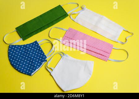 Five colored different reusable medical masks on yellow isolated background. Hygienic antimicrobial, antiviral tissue masks. Closeup of the concept of Stock Photo